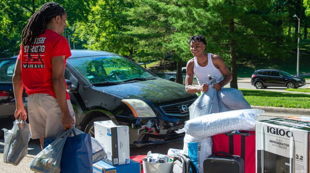 Two students with all their belongings moving into the dorms/residence halls.