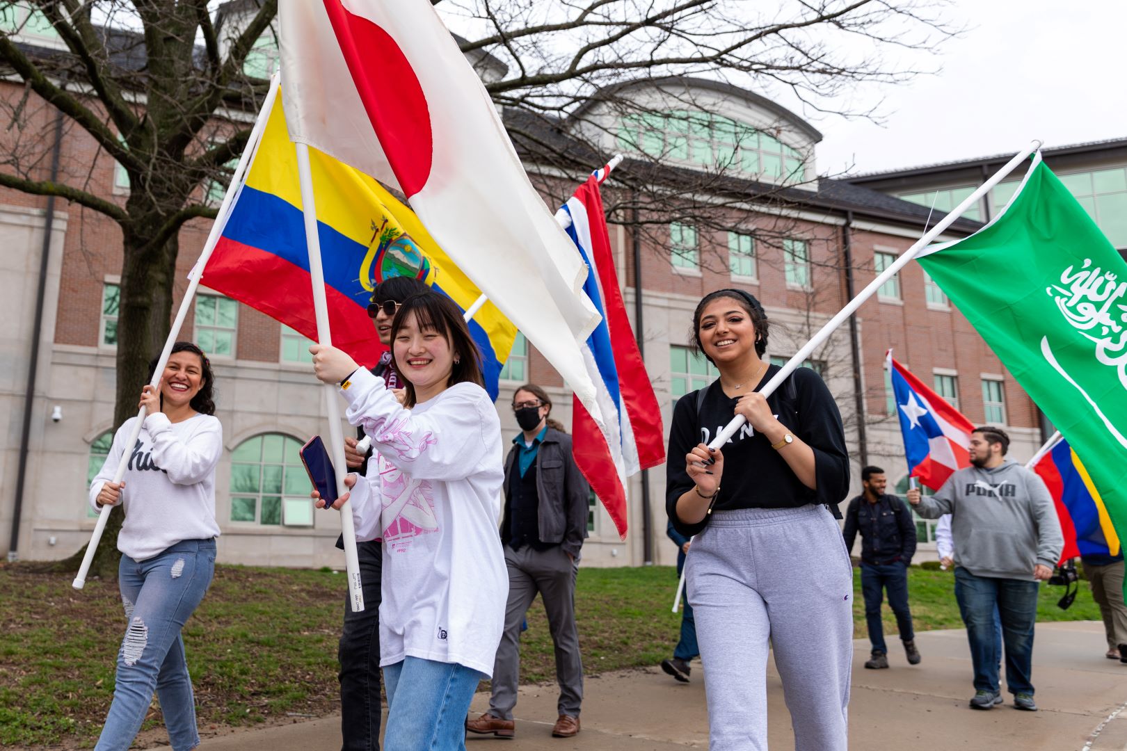 students from various countries carrying their flags across campus