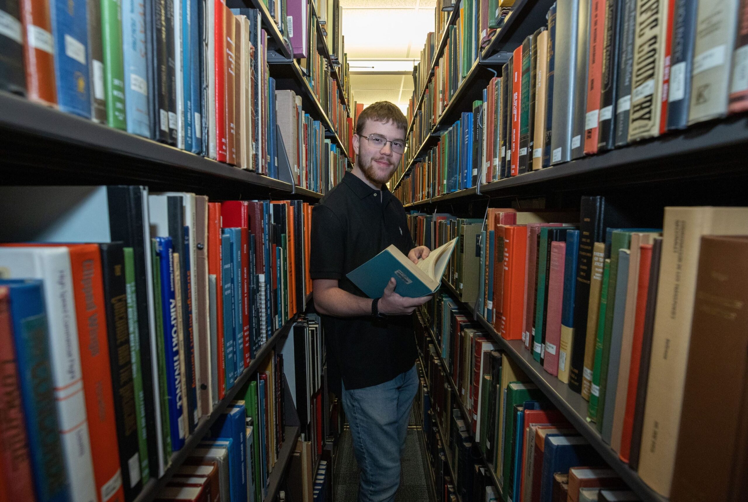 Student displaying books in Morris Library. library lovers month
