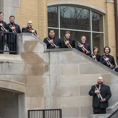 Musicians standing on stairs, holding trumpets.