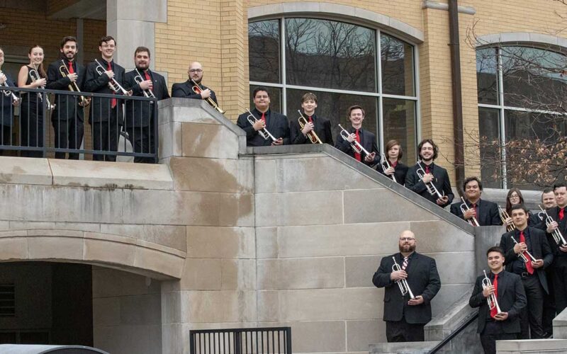 Musicians standing on stairs, holding trumpets.