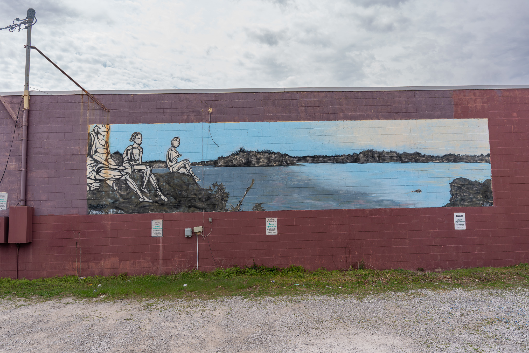 Long-lasting Carbondale mural, people sitting on rocks near water.