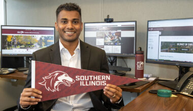 A man holding a pennant with a dog head that says Southern Illinois.