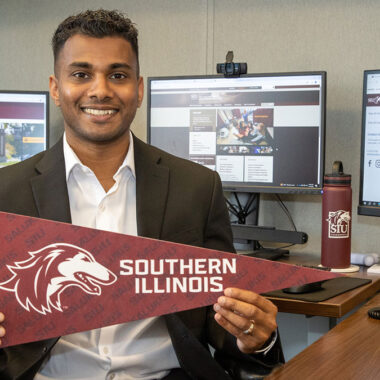 A man holding a pennant with a dog head that says Southern Illinois.