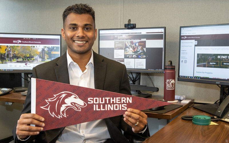 A man holding a pennant with a dog head that says Southern Illinois.