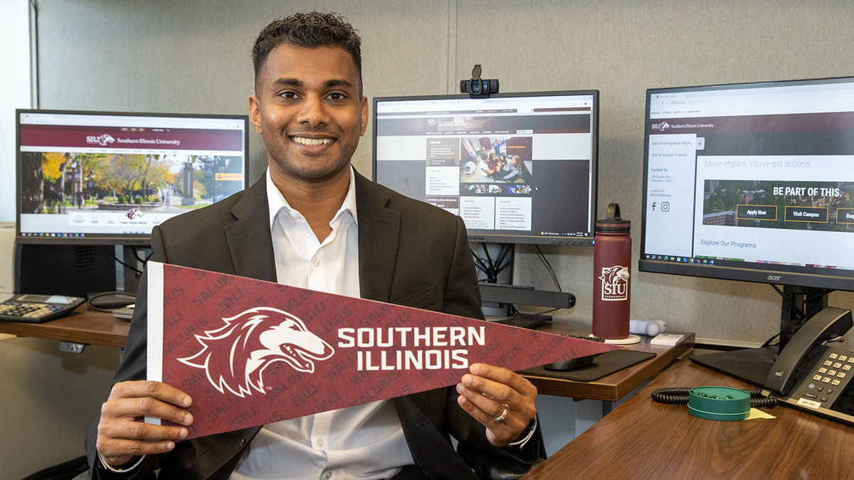 A man holding a pennant that has a dog head and says Southern Illinois.