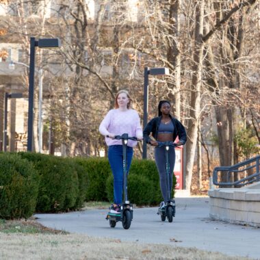 students riding veo scooters