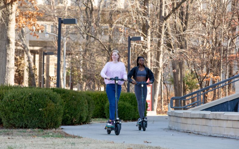 students riding veo scooters