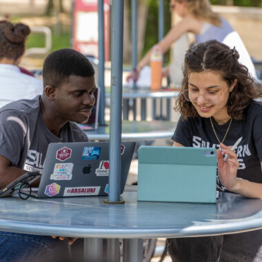 students looking at a laptop together outside