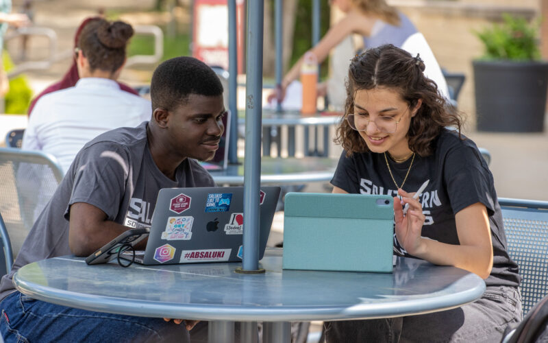 students looking at a laptop together outside