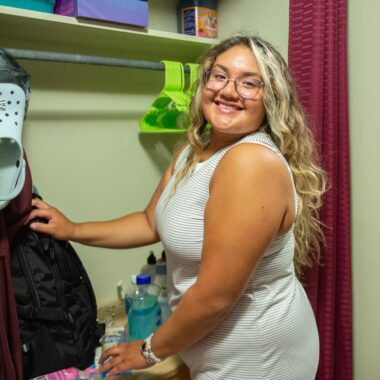 student putting clothes in their closet in their residence hall
