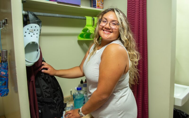 student putting clothes in their closet in their residence hall