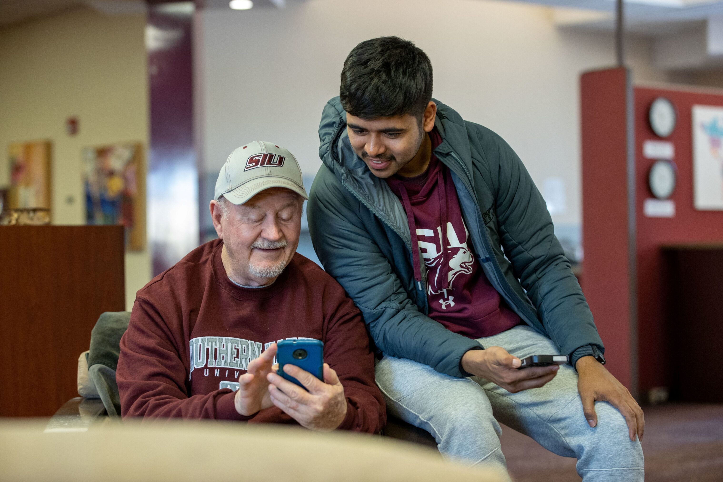 Individuals at International Coffee Hour intrigued in a phone