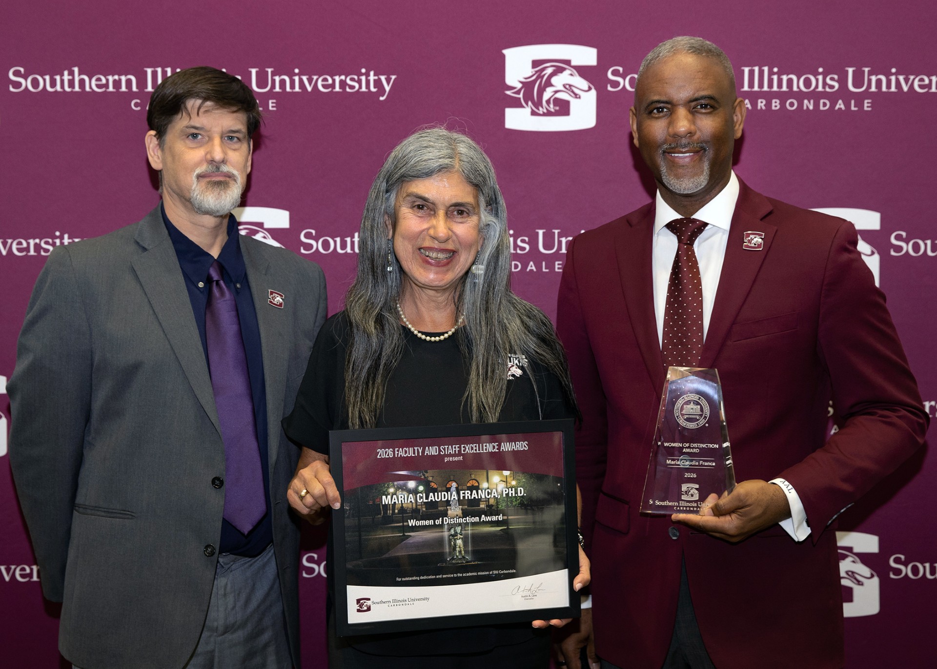 Maria Claudia Franca (center) receives the 2026 Staff Excellence Award.