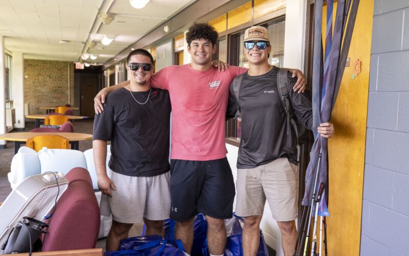 students posing for the camera outside their residence hall room on move in day