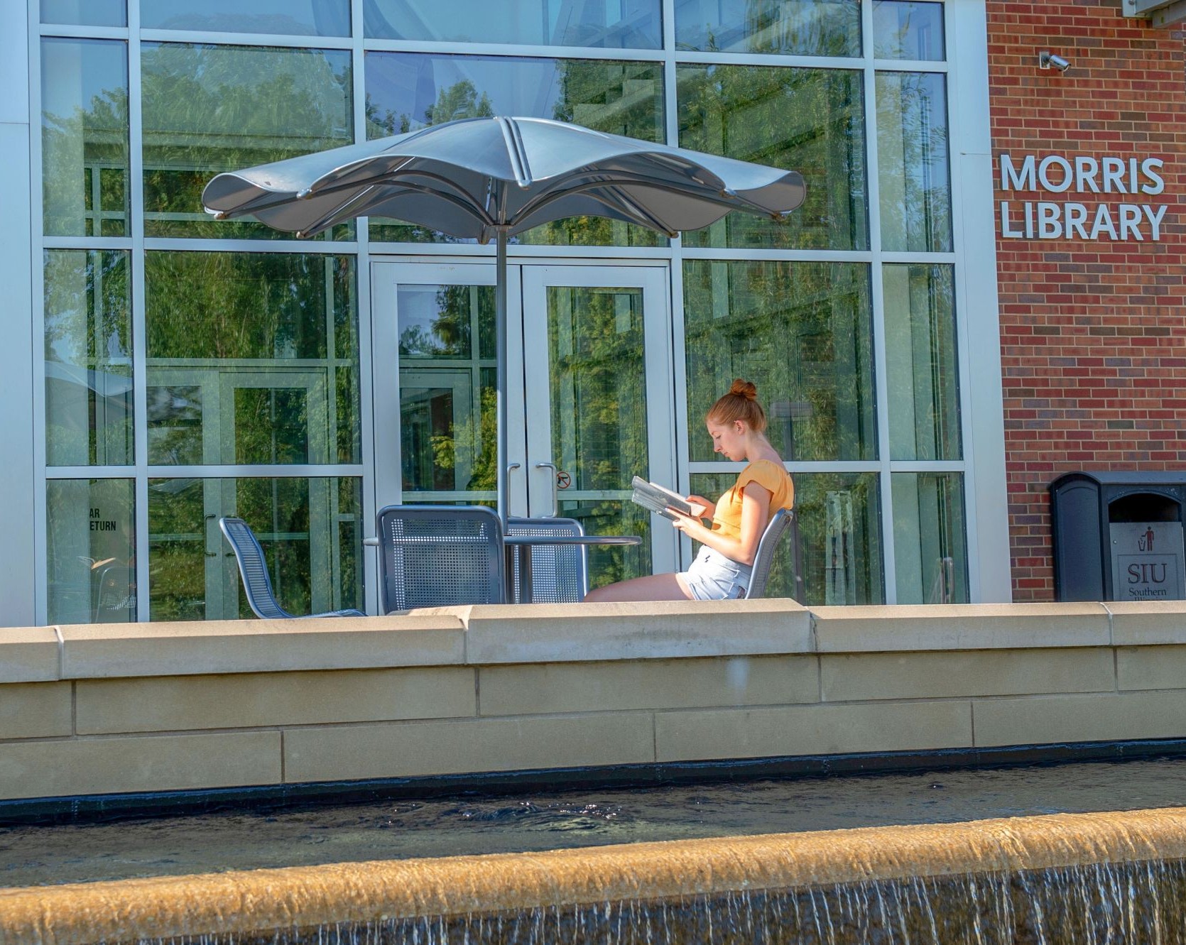 student reading by the fountain outside Morris Library